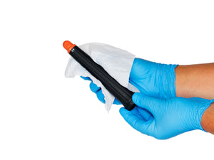 Two hands in nitrile gloves cleaning a Dyson Airwrap barrel attachment with a sanitization wipe