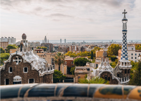Barcelona skyline seen from Park Güell, with Gaudí's mosaic-tiled pavilions in the foreground