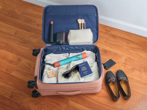 Carry-on suitcase packed with a European Dyson Airwrap, US passport and sunglasses for Europe travel