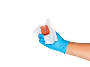 Two hands in nitrile gloves cleaning a Dyson Airwrap filter with a sanitization wipe
